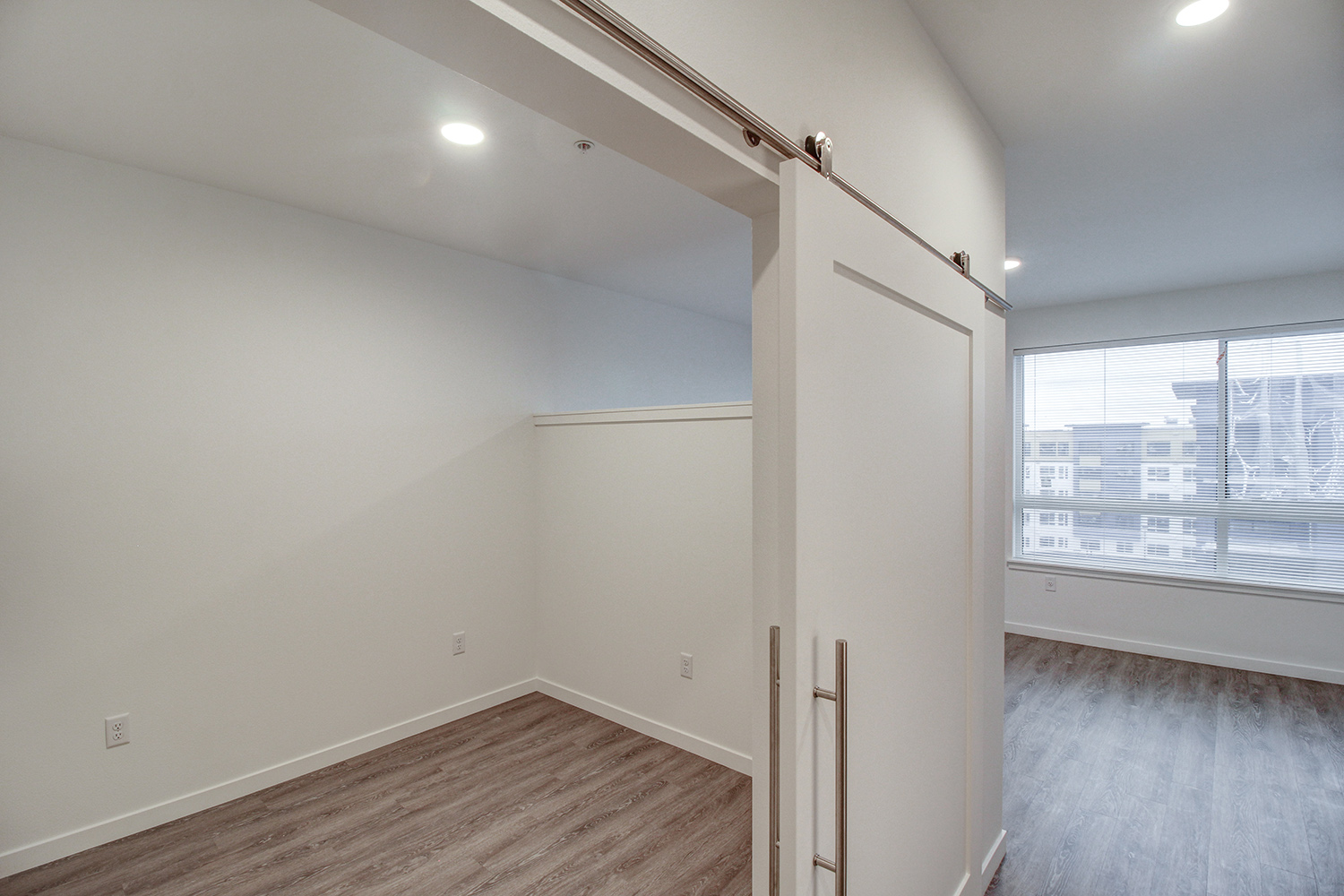 Bedroom with sliding doors in a studio apartment at The Woods at Alderwood in Lynnwood, WA.