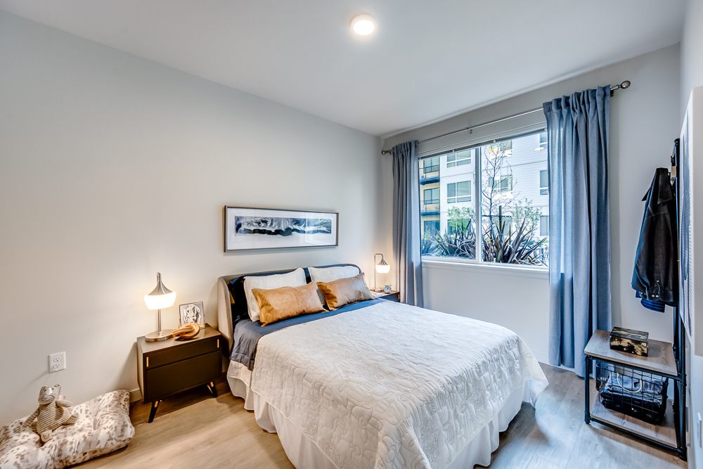 Bedroom with wooden floors and large windows at The Woods at Alderwood in Lynnwood, WA.