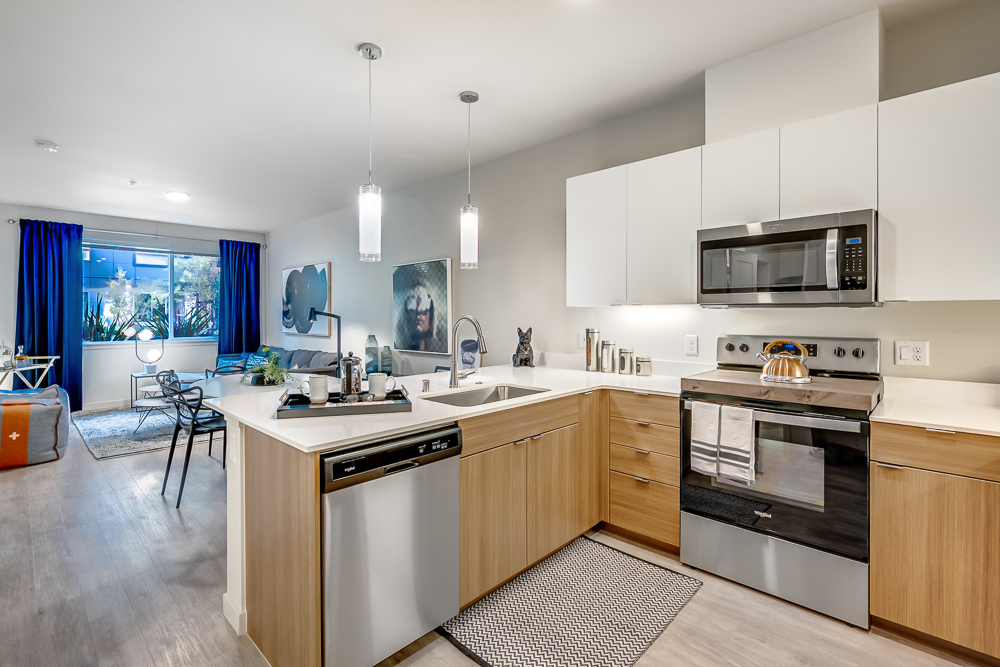Spacious kitchen area connected to the living room area in an apartment at The Woods at Alderwood in Lynnwood, WA.