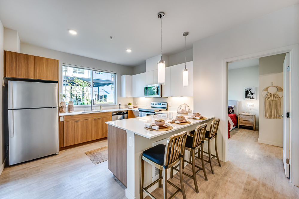 Kitchen with kitchen island and barstools next to the bedroom at The Woods at Alderwood in Lynnwood, WA.